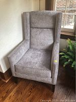 Front view of grey upholstered armchair showing high back and armrests