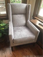Front view of grey fabric wingback armchair
