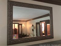 Front view of rectangular wall mirror with ornate carved frame and beveled glass