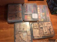 Four clear plastic storage cases containing wood-mounted rubber stamps and a watercolor paint set