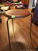Side view of stool showing walnut-tone round wooden seat and chrome-plated tripod legs