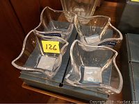 Four clear glass dishes with Villeroy & Boch blue label, stacked and shown in original box on wooden surface.