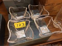 Photo showing four clear glass dishes with wavy edges sitting on a box, each with Villeroy & Boch label.