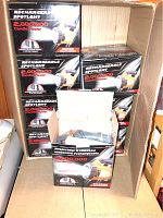 Case containing eight boxes of rechargeable spotlight lanterns, each with labeling showing 2,000,000 candle power.