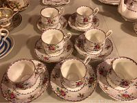 Seven Royal Albert Petit Point tea cups with matching saucers, displaying floral petit point pattern and gold trim.