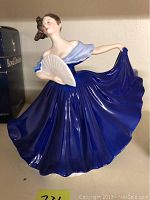 Front angle showing the figurine in flowing blue gown holding a white fan.