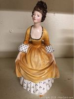 Front view of the Royal Doulton porcelain figurine showing detailed yellow gown and face.