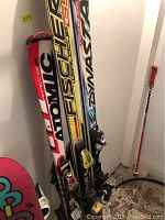 Three pairs of skis including Atomic Race Red, Fischer Worldcup GS Yellow, Dynastar Course WB Blue with bindings and one red-handled ski pole