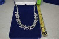 Full view of the rhinestone necklace in a blue velvet box, showing approximately 17 inches length with a measuring tape alongside.