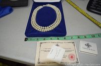 Full necklace displayed in blue velour-lined box with measuring tape and certificate of authenticity visible.