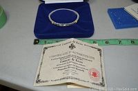Bracelet in blue velvet box with certificate of authenticity and measuring tape in background