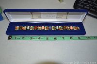 Wide shot of the full bracelet laid inside the blue box with a tape measure showing approximately 8.5 inches length.