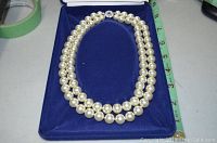 Double strand faux pearl necklace approximately 18 inches long displayed in royal blue velvet box with measuring tape beside it showing length.