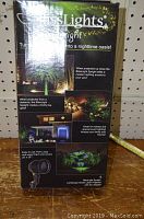 Front side of the box showing BlissLights Spright branding and images of projected light effects including mood lighting and firefly-like glow.