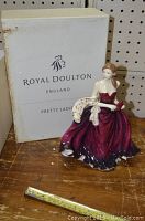 Porcelain figurine seated woman in maroon gown with box shown