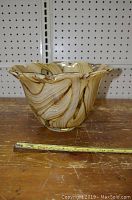 Front view of the decorative crystal bowl showing swirling wood grain pattern and wavy rim with measuring tape indicating size.