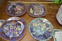 Four collector plates featuring floral and bird designs with one certificate of authenticity visible