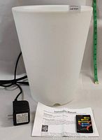 White trapezoidal LED planter new, showing external shape, power adapter, and instruction manual on the side.