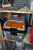 Closed large resin tool box on shelf with visible amber compartments on lid