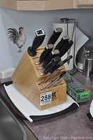 Front view of wooden knife block with six knives, sharpening steel and scissors atop two cutting boards