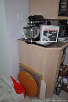 Black KitchenAid stand mixer on countertop alongside boxed food grinder attachment