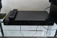 Front view of the black Pioneer Blu Ray player with remote placed on top.