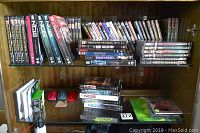 Two wooden shelves filled with DVD cases and three wireless mice on lower shelf