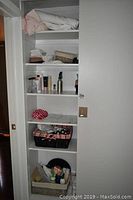 Full view of closet shelving with towels, bath mats, tissue, and personal care items in baskets