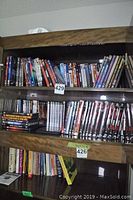 Full view of DVDs and books arrayed on multiple wooden shelves showing the large collection including TV series and movies