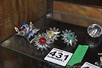 Photo showing three clear Swarovski crystal daisies with colored centers and the metal holder with multicolored crystal tulips.