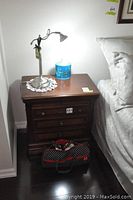 Front view of nightstand and lamp, showing overall appearance and scale next to bed.