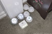 Eight assorted internal motion sensor lights arranged on carpet near wall and furniture.