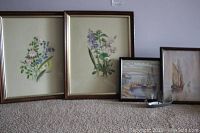 Two framed botanical prints and two small boat watercolours displayed on floor, along with a metal boat model.