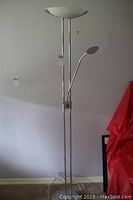 Full view of the chrome floor lamp showing the main upward facing shade and the lower adjustable reading light arm.