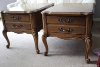 Pair of Bassett Furniture end tables side by side on carpet, showing scalloped edge and drawer face with metal handles