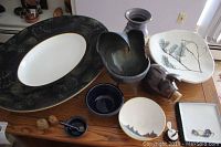 Photo showing all the ceramic and clay items including platter, bowls, piggy bank, figurines, and vase on a wooden table.