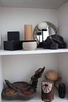 Shelf showcasing grouped candles, candle holders, and a round mirror
