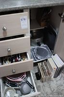 Drawer with stainless steel cutlery and various kitchen tools such as peelers, mashers, and butter knives