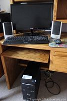 Full view of computer setup including LG monitor, Gateway speakers, Delux keyboard, Logitech mouse, and Compaq Presario desktop tower under oak desk.