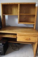 Full view of the desk with attached hutch showing the shelving and oak grain finish