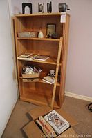 Full view of wooden bookshelf with various items including books, a yardstick, and miscellaneous small household items on shelves.