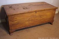 Full view of the cedar lined wooden chest showing surface wear and carved feet.