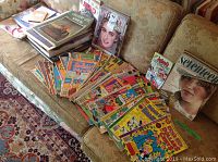 Wide view of couch showing multiple vintage magazines including Archie comics, MAD, Seventeen, and books.