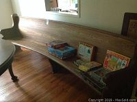 Side view of long curved wooden bench with board seat and back. Items like puzzles placed on seat show the scale and length.