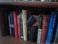 Shelf with a variety of books including hardcovers and paperbacks with titles such as 'Joy's Railway', 'The Piping Times', 'Filma: An Anthology'