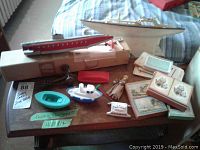 Overview of wood side table holding toy boats, playing cards, and a small carved figurine.