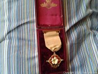 Close-up of antique army award medal in maroon lined case showing medal design and original ribbon