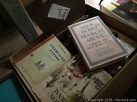 Open cardboard box with several books visible, including 'Men Who March Away' and 'Exercises for Arms'.