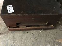 Front view of large dark wood chest with bottom drawer partially open showing missing pull handle and keyhole on front.