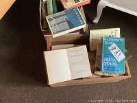 A box of assorted books with various subjects visible including 'The Journey's Echo' by Freya Stark and 'The Atmosphere' open inside the box.
